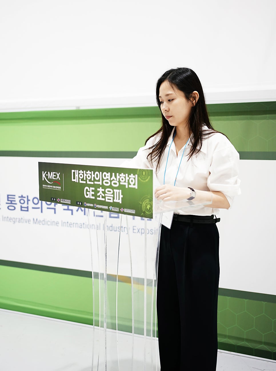 한 여성이 연단 뒤에서 발표 자료를 보고 있다 — 대한한의영상학회 초음파 약침·도침 강의 | 서울 바로한의원 문지현 원장