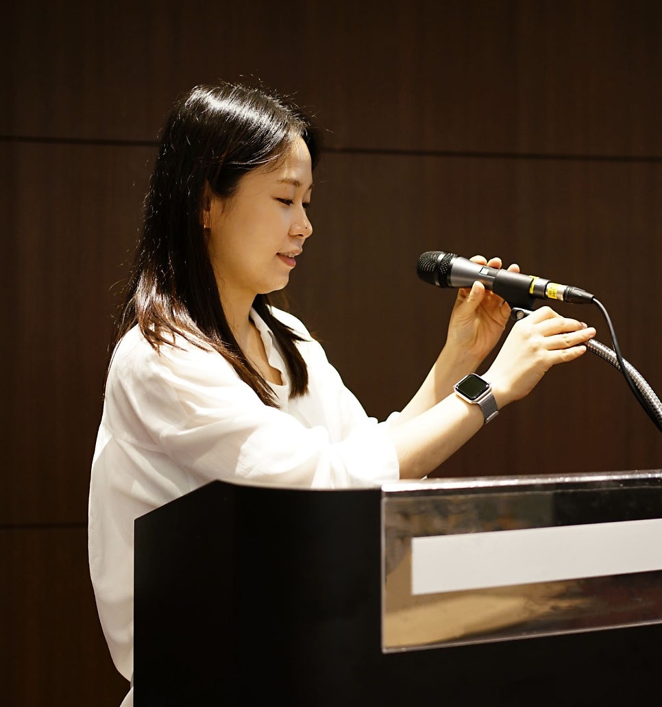 흰 셔츠를 입은 여성이 검은색 연단 뒤에서 마이크를 잡고 이야기하고 있다 — 대한한의영상학회 초음파 약침·도침 강의 | 서울 바로한의원 문지현 원장