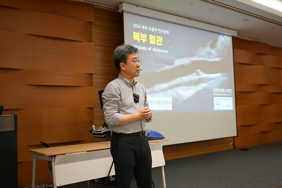 강사가 복부 초음파 영상이 보이는 화면 앞에서 발표하고 있는 모습 — 대한한의영상학회 초음파 약침·도침 강의 | 서울 바로한의원