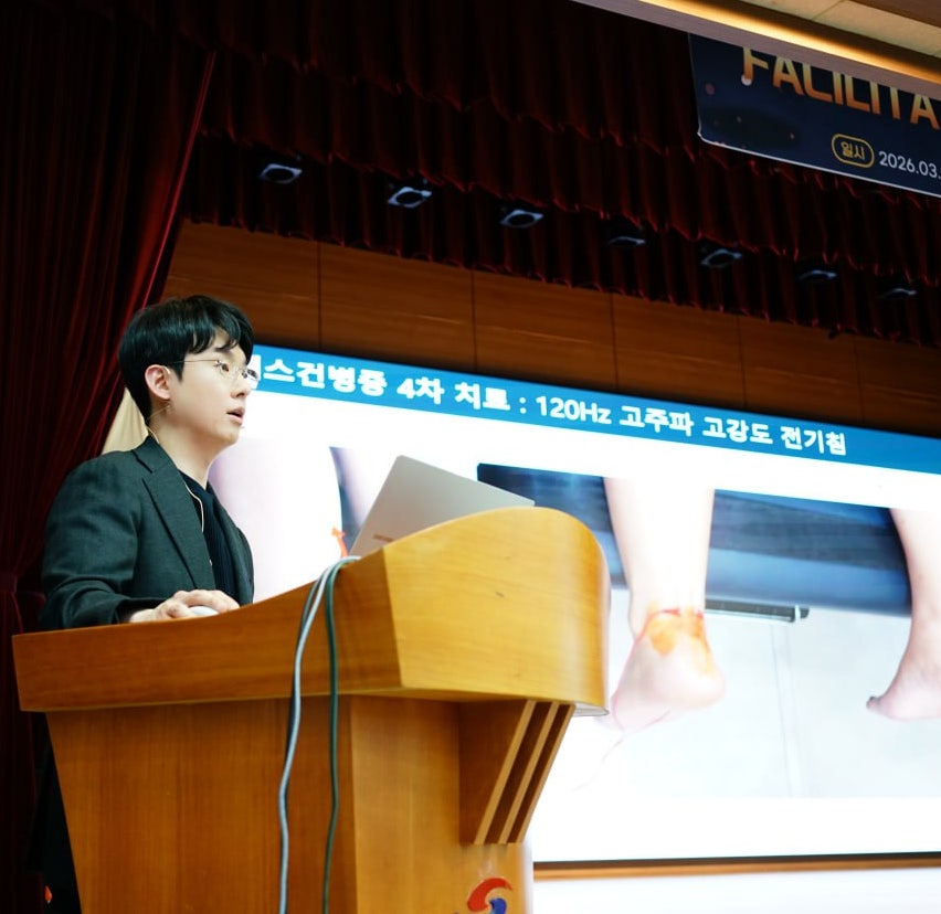 강단에서 발표하는 남성과 아킬레스건 병증 치료에 대한 내용 및 발 사진이 보이는 스크린 — 대한한의영상학회 초음파 약침·도침 강의 | 서울 바로한의원 안태석 원장