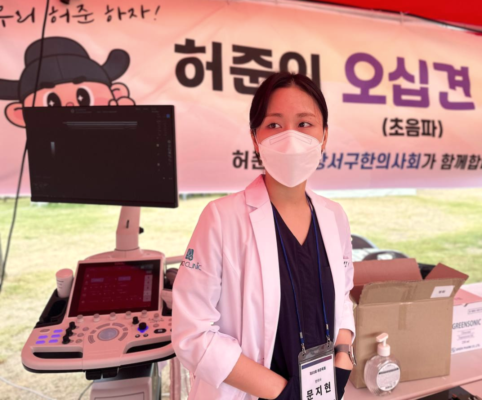 마스크를 쓴 여성이 흰색 가운을 입고 초음파 기기 옆에 서 있는 모습 — 초음파 정밀 진단 | 서울 바로한의원 초음파 약침·도침·침도