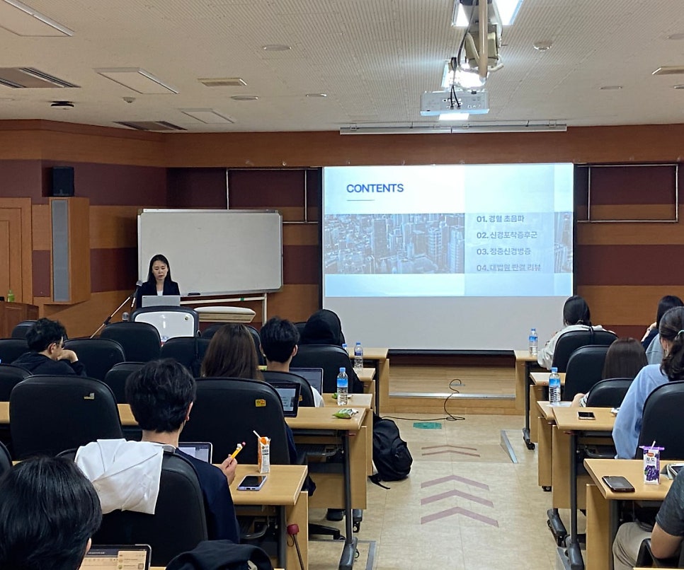 강의실에서 발표자가 강단에 서서 강연하고 있으며, 스크린에는 'CONTENTS'와 함께 '경혈 초음파' 등의 내용이 보인다. 여러 명의 청중이 앉아 발표를 듣고 있다 — 대한한의영상학회 초음파 약침·도침 강의 | 서울 바로한의원