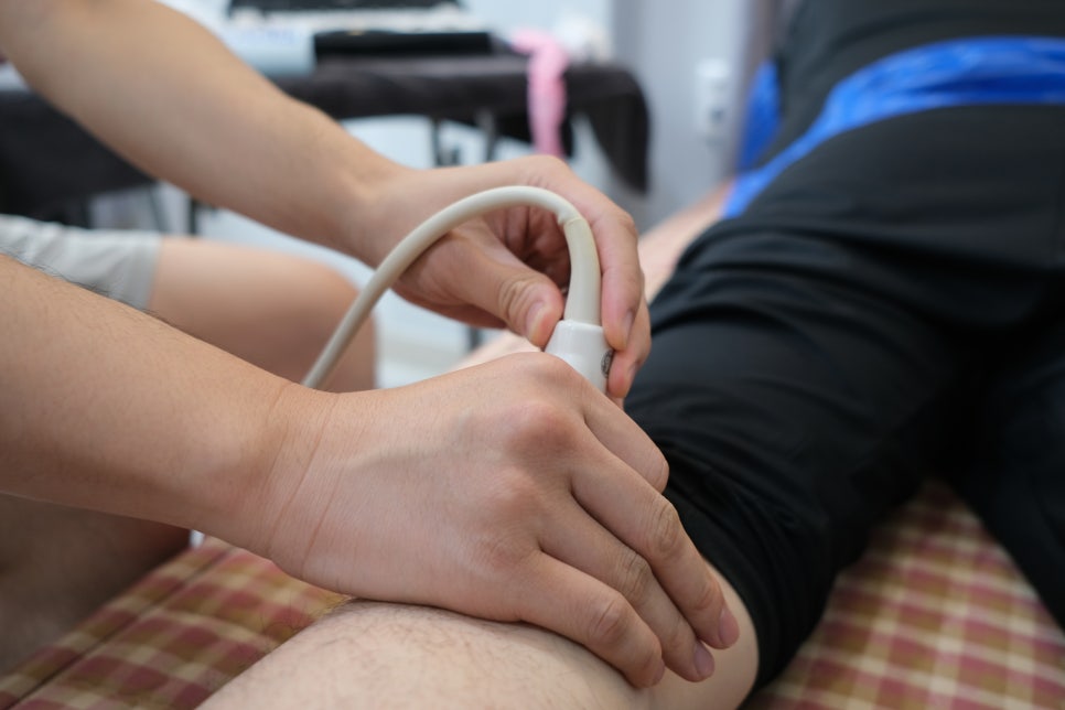 한 사람이 다른 사람의 다리에 초음파 탐촉자를 대고 있는 모습 — 초음파 유도하 약침 시술 | 서울 바로한의원