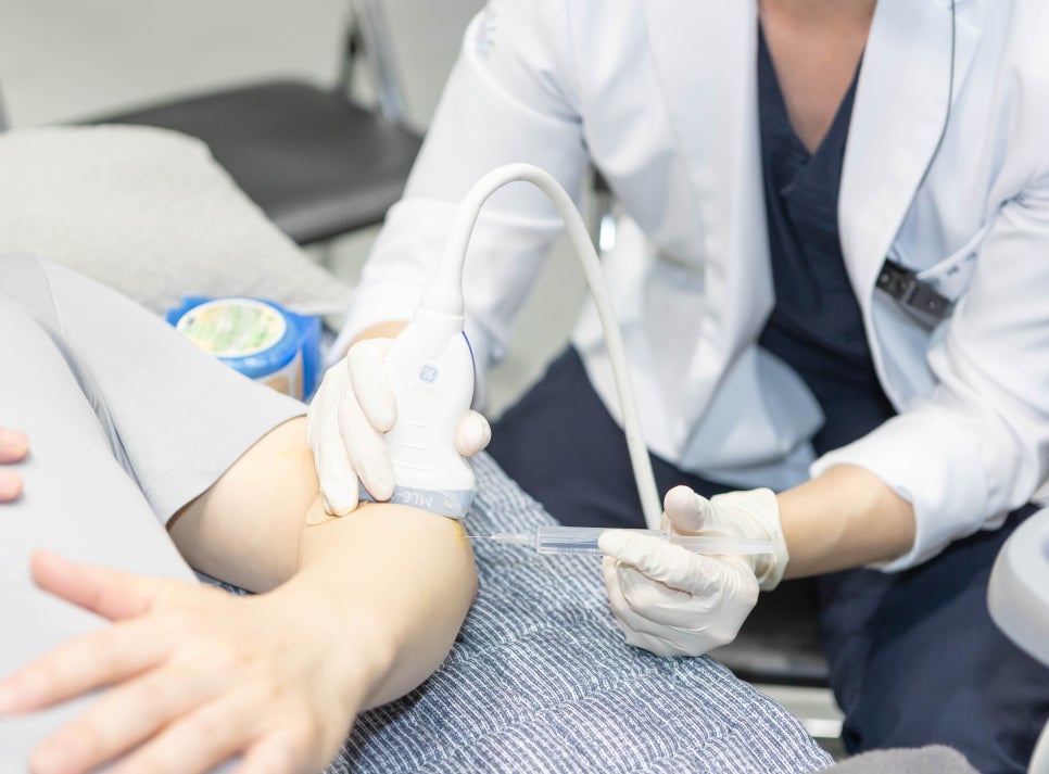 한의사가 환자의 팔에 초음파를 보며 주사 시술을 하는 모습 — 초음파 유도하 약침 시술 | 서울 바로한의원