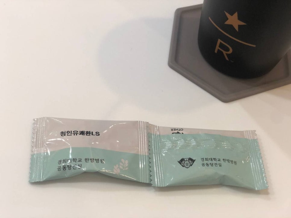 흰색 테이블 위에 놓인 청인유쾌환LS 포장과 검은색 컵 — 서울 바로한의원 초음파 약침·도침