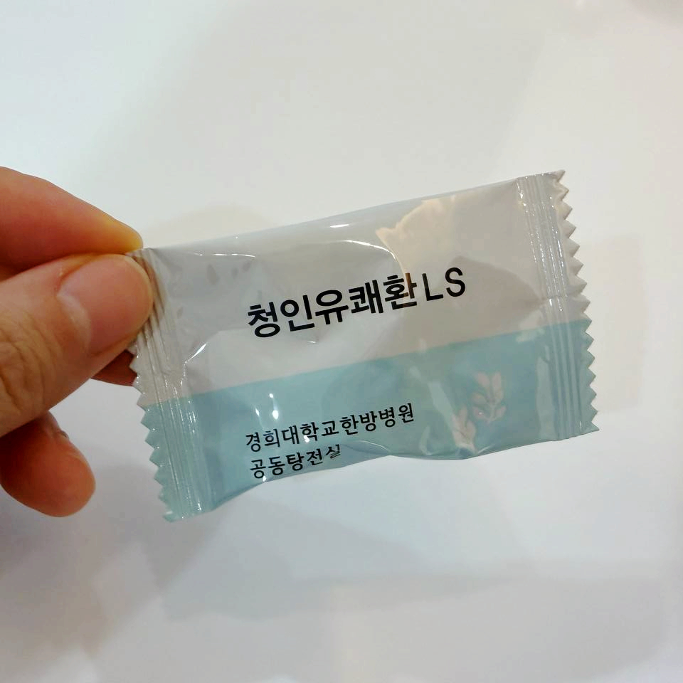 손이 '청인유쾌환 LS'와 '경희대학교한방병원 공동탕전실'이 적힌 은색 포장지를 들고 있는 모습 — 서울 바로한의원 초음파 약침·도침