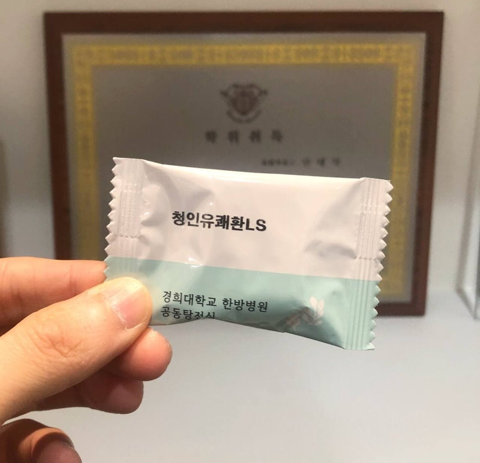 손이 '청인유쾌환LS'라고 적힌 흰색과 연두색 한약 포를 들고 있는 모습이다 — 서울 바로한의원 초음파 약침·도침