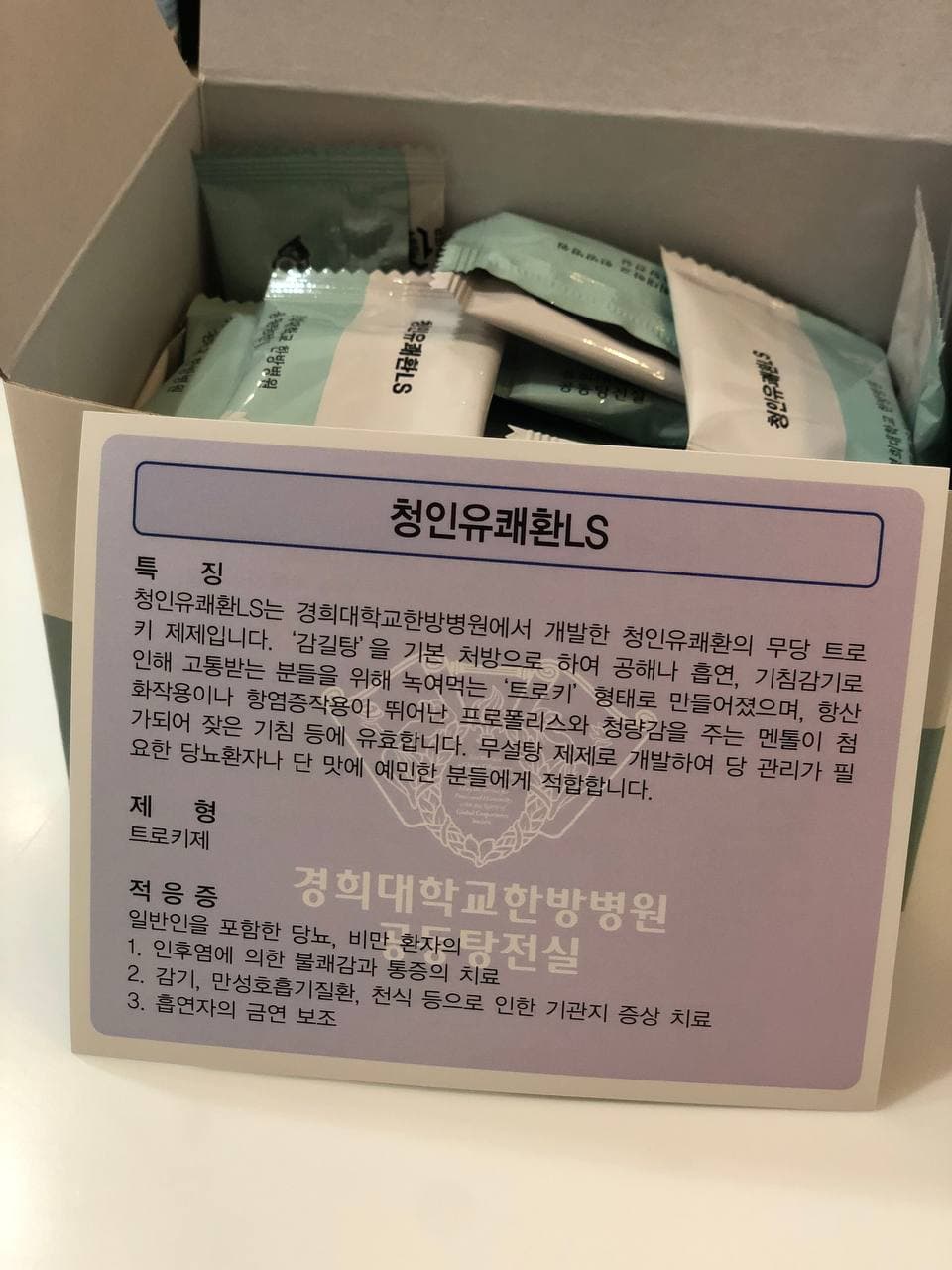 개봉된 상자에 개별 포장된 청인유쾌환LS 트로키가 담겨 있으며, 제품 정보가 적힌 안내문이 앞에 있습니다 — 서울 바로한의원 초음파 약침·도침