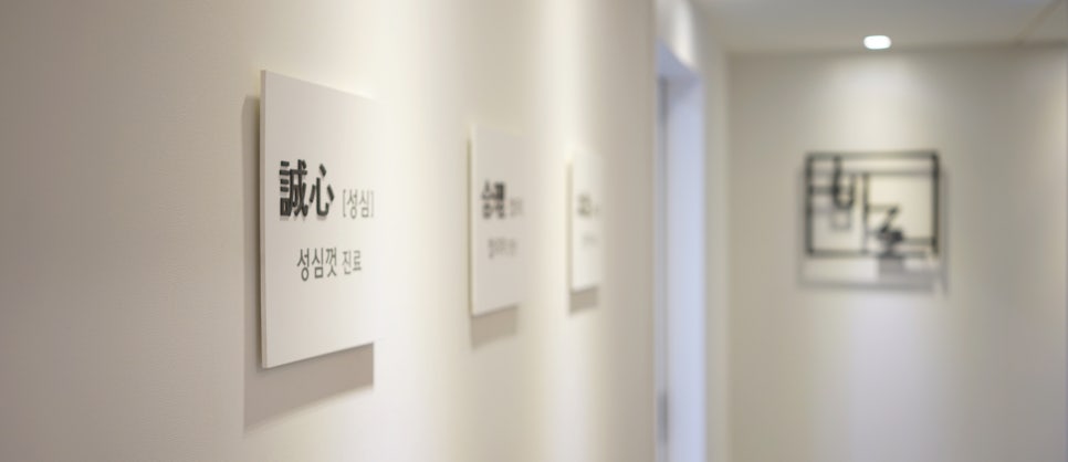 한의원 복도에 '성심껏 진료'라고 적힌 표지판이 걸려 있습니다 — 서울 바로한의원 초음파 약침·도침