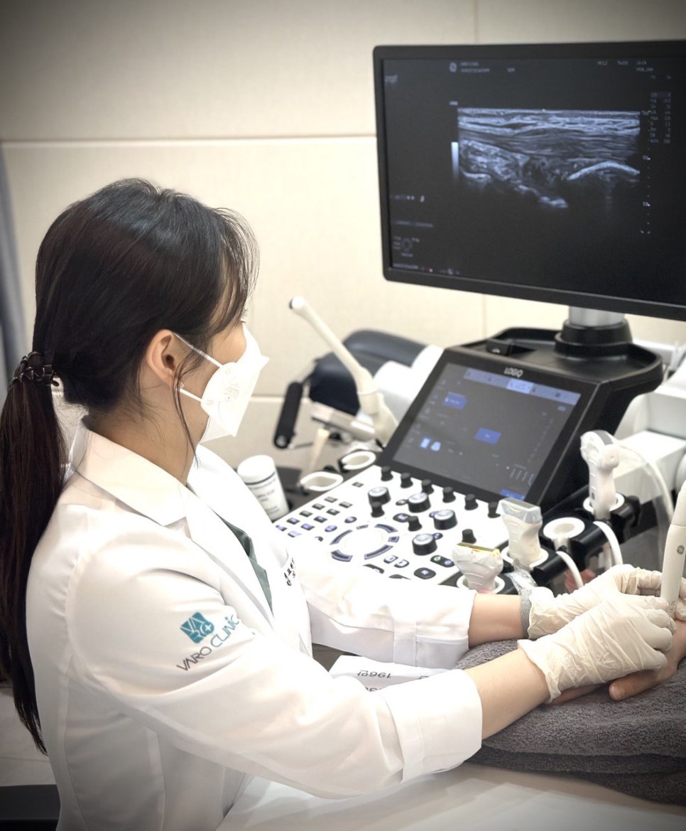 마스크를 착용한 의료진이 환자의 손목에 초음파 검사를 진행하며 모니터를 보고 있다 — 초음파 정밀 진단 | 서울 바로한의원 초음파 약침·도침·침도