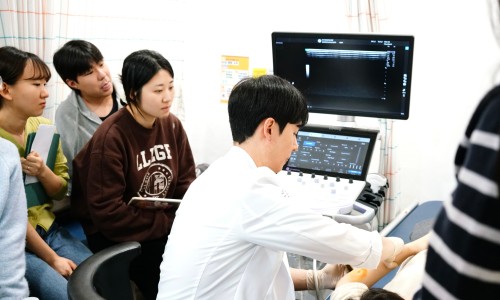 한의사가 초음파 화면을 보며 환자의 팔에 시술하고 여러 명이 이를 지켜보고 있는 모습 — 초음파 유도하 약침 시술 | 서울 바로한의원