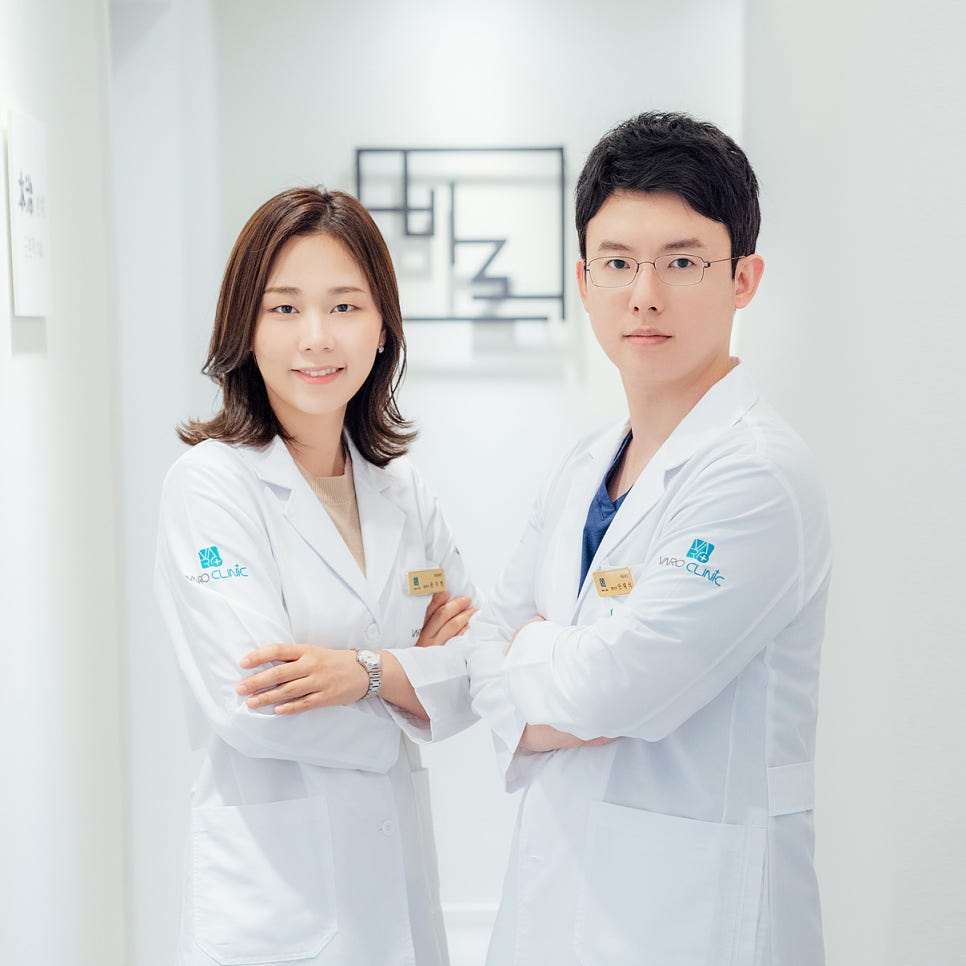 흰색 가운을 입은 남녀 한의사 두 명이 팔짱을 끼고 한의원 복도에 서서 카메라를 보고 있다 — 서울 바로한의원 초음파 약침·도침