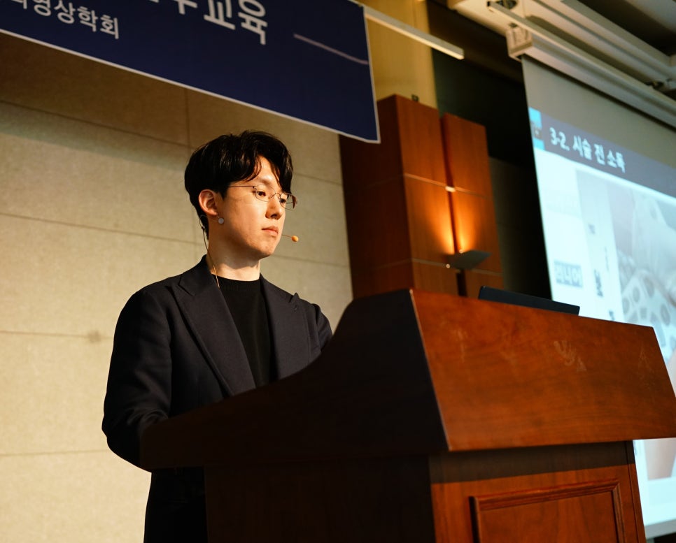 강단에서 마이크를 착용한 안경 쓴 남성이 발표하는 모습 — 대한한의영상학회 초음파 약침·도침 강의 | 서울 바로한의원 안태석 원장