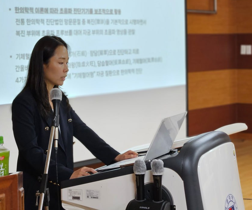 강단에서 마이크를 잡고 한의학 및 초음파 진단 관련 발표를 하는 여성 — 대한한의영상학회 초음파 약침·도침 강의 | 서울 바로한의원 문지현 원장