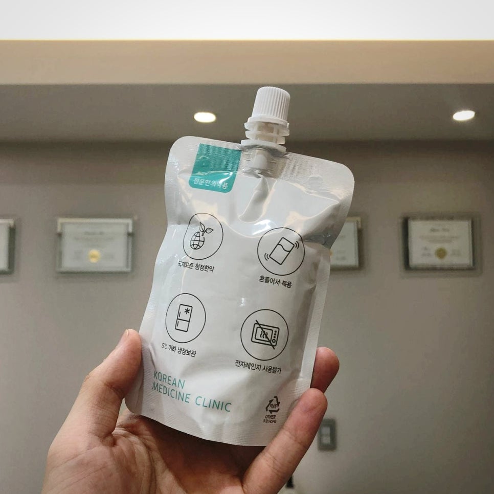 손이 'KOREAN MEDICINE CLINIC'이라고 적힌 흰색 파우치를 들고 있다 — 서울 바로한의원 초음파 약침·도침