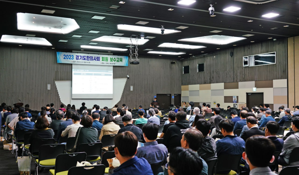 강당에 앉아 스크린을 바라보는 많은 사람들의 모습으로, 스크린에는 '2023 경기도한의사회 회원 보수교육'이라는 글자가 보인다 — 대한한의영상학회 초음파 약침·도침 강의 | 서울 바로한의원