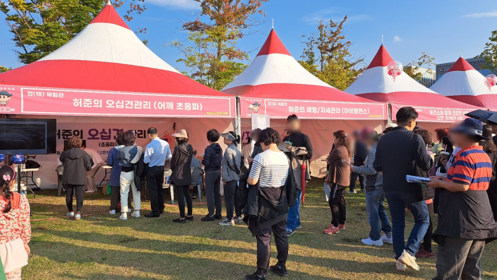 강서구 허준축제 야외 부스에서 사람들이 어깨 초음파 체험을 위해 모여 있다. 부스 내 화면에 초음파 영상이 표시되어 있다 — 초음파 정밀 진단 | 서울 바로한의원 초음파 약침·도침·침도