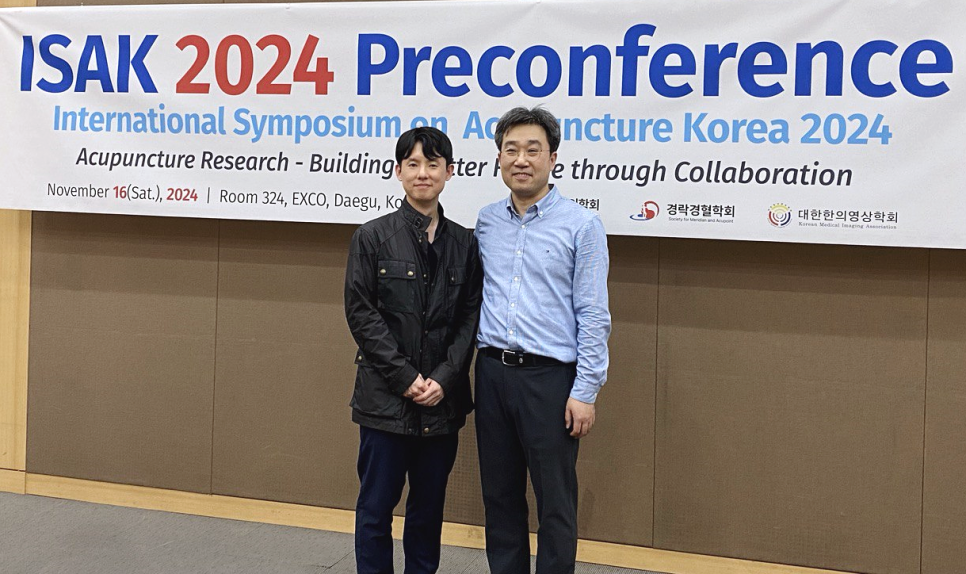 ISAK 2024 국제학술대회 배너 앞에서 두 남자가 서 있는 모습 — 대한한의영상학회 초음파 약침·도침 강의 | 서울 바로한의원 안태석 원장