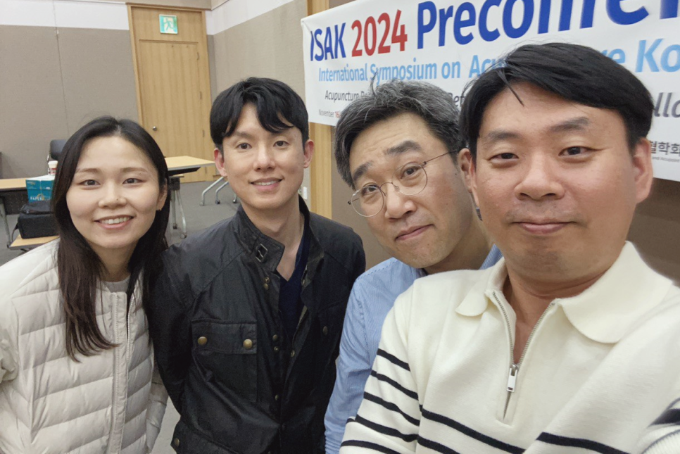 ISAK 2024 국제학술대회 현장에서 네 명의 사람들이 카메라를 보며 미소 짓고 있다 — 서울 바로한의원 초음파 약침·도침