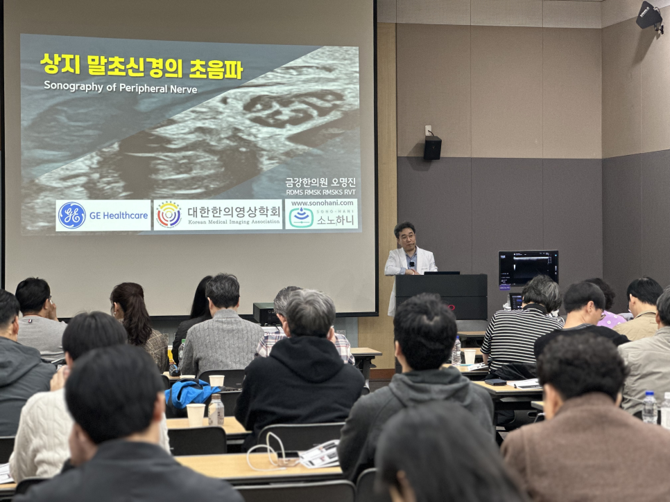 학회에서 한의사가 상지 말초신경 초음파에 대해 발표하고 있으며, 스크린에 초음파 영상과 발표 제목이 보입니다 — 대한한의영상학회 초음파 약침·도침 강의 | 서울 바로한의원