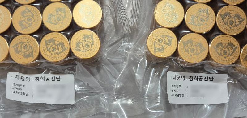금색의 둥근 한약 환들이 투명한 비닐에 포장되어 트레이에 담겨 있으며, '제품명: 경희공진단' 라벨이 붙어 있다 — 서울 바로한의원 초음파 약침·도침