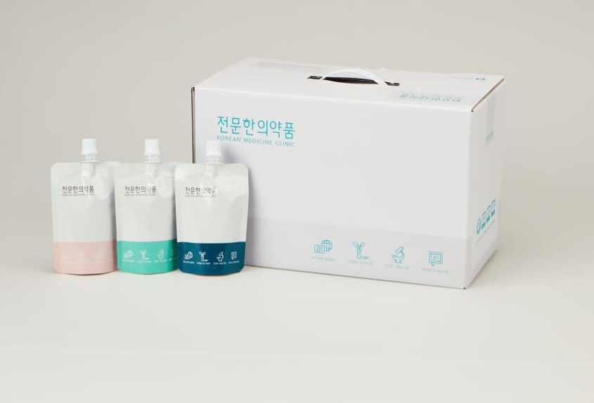 세 가지 색상의 파우치 한약과 흰색 상자가 함께 놓여 있는 모습 — 서울 바로한의원 초음파 약침·도침