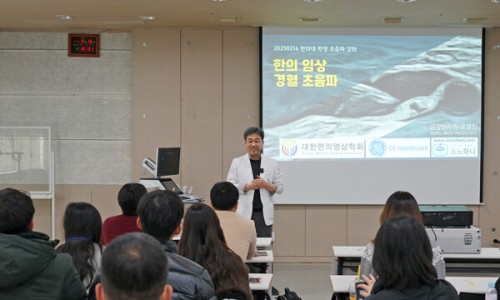 강사가 청중 앞에서 '한의 임상 경혈 초음파' 제목의 슬라이드를 띄운 채 강연하는 모습 — 대한한의영상학회 초음파 약침·도침 강의 | 서울 바로한의원