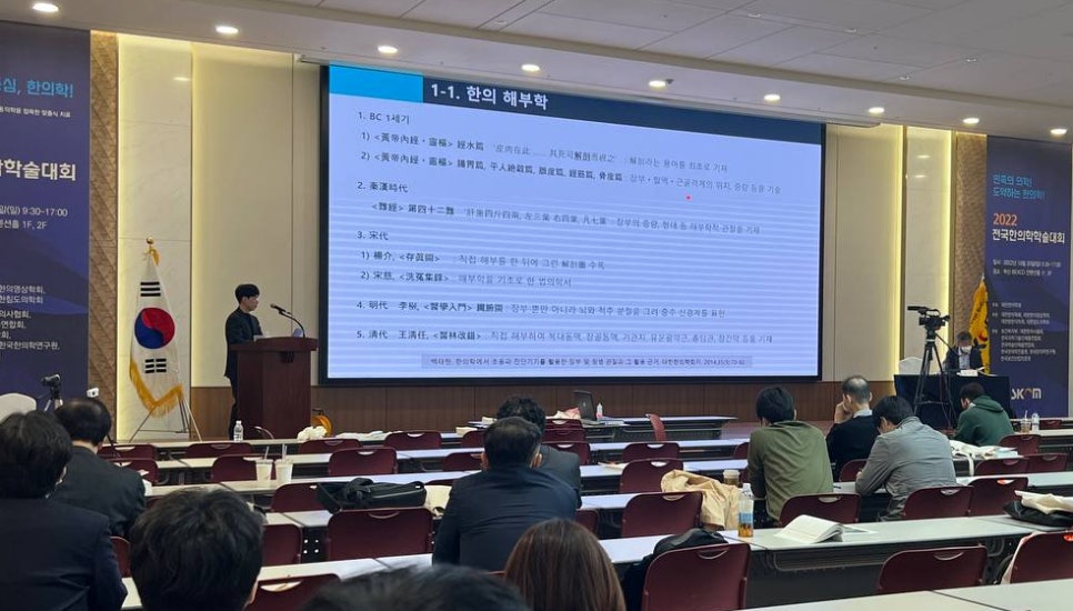 한의학 학술대회에서 연사가 '한의 해부학'이라는 제목의 발표를 하고 있으며, 청중들이 강당에 앉아 있다 — 대한한의영상학회 초음파 약침·도침 강의 | 서울 바로한의원