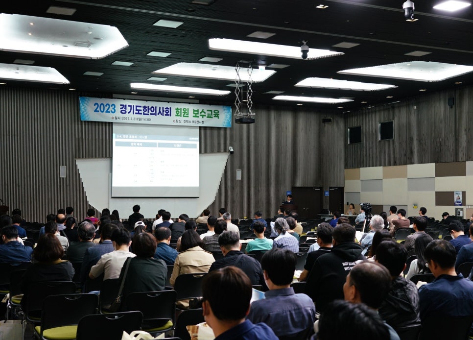 강당에 많은 사람들이 앉아 스크린에 비친 발표를 보고 있으며, '2023 경기도한의사회 회원 보수교육' 배너가 걸려 있다 — 대한한의영상학회 초음파 약침·도침 강의 | 서울 바로한의원