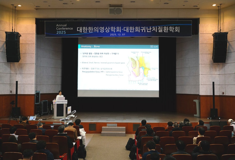 한의영상학회 학술대회에서 연자가 무대 위에서 발표하고 있으며, 스크린에는 뼈 해부학 관련 슬라이드가 보인다 — 대한한의영상학회 초음파 약침·도침 강의 | 서울 바로한의원