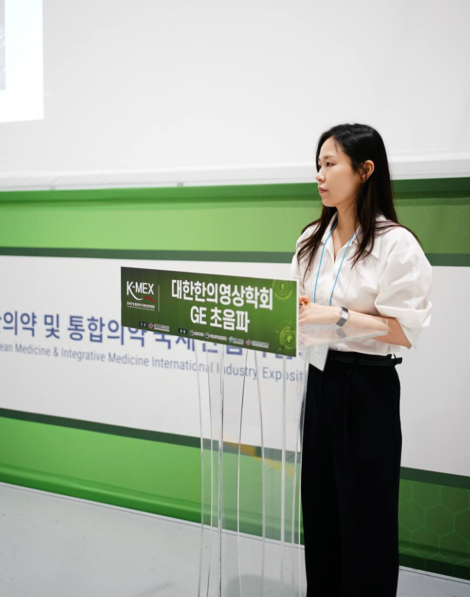 대한한의영상의학회 GE 초음파라고 적힌 현수막 앞에서 발표하는 여성 — 대한한의영상학회 초음파 약침·도침 강의 | 서울 바로한의원 문지현 원장
