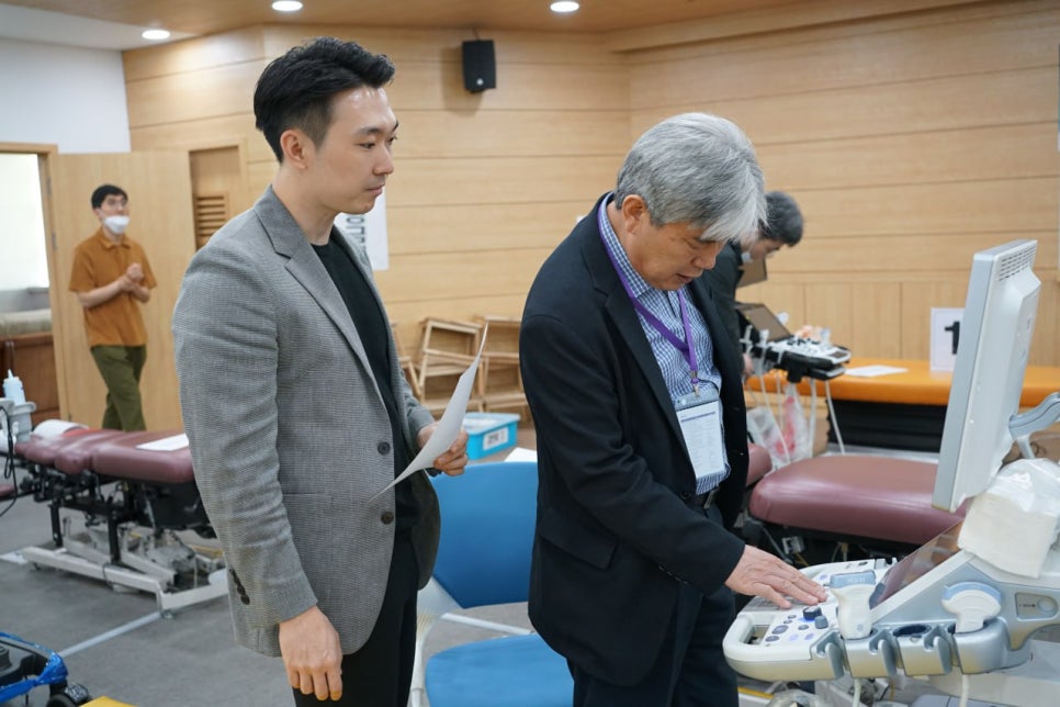 학술대회에서 한 남성이 초음파 기기를 조작하고 다른 남성이 옆에서 지켜보고 있다 — 대한한의영상학회 초음파 약침·도침 강의 | 서울 바로한의원 안태석 원장