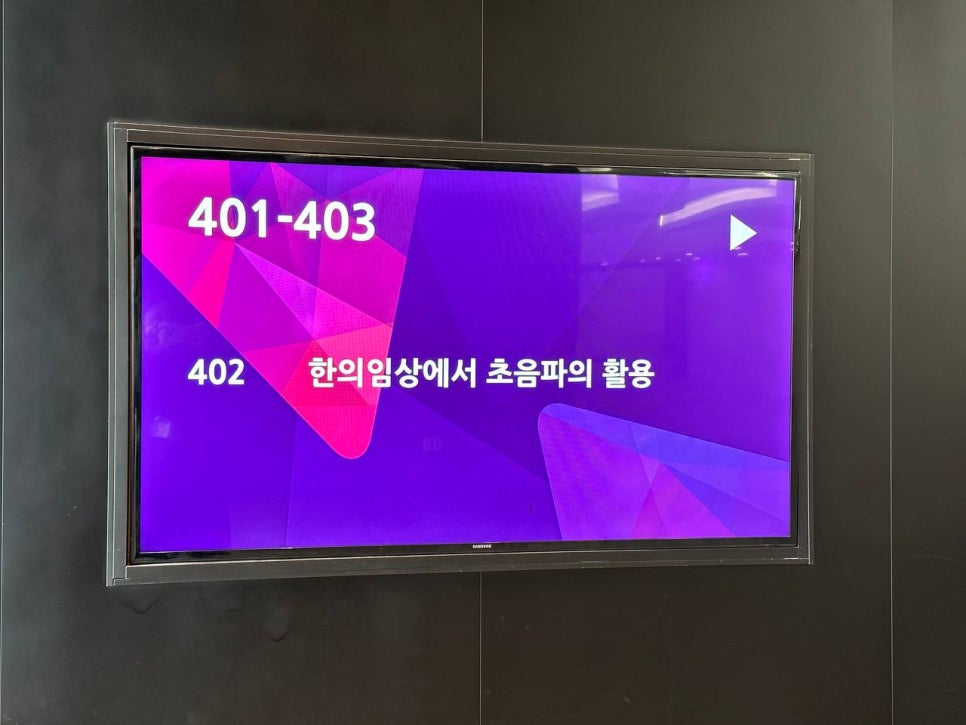 검은 벽에 걸린 디지털 화면에 '401-403', '402' 숫자와 '한의임상에서 초음파의 활용'이라는 문구가 표시되어 있다 — 초음파 정밀 진단 | 서울 바로한의원 초음파 약침·도침·침도