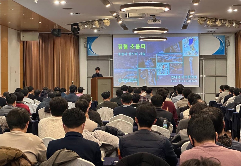 강사가 청중 앞에서 초음파 관련 내용을 발표하는 강연장 모습 — 대한한의영상학회 초음파 약침·도침 강의 | 서울 바로한의원