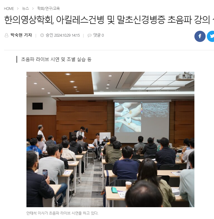 강연장에서 강사가 화면에 초음파 시술 장면을 보여주며 라이브 시연을 하고 있으며, 여러 명의 수강생들이 이를 지켜보고 있다 — 대한한의영상학회 초음파 약침·도침 강의 | 서울 바로한의원