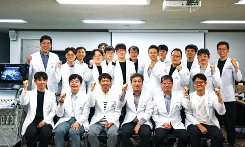 흰색 가운을 입은 남성들이 초음파 기기와 모니터가 있는 실내에서 주먹을 쥐고 포즈를 취하고 있다 — 초음파 정밀 진단 | 서울 바로한의원 초음파 약침·도침·침도