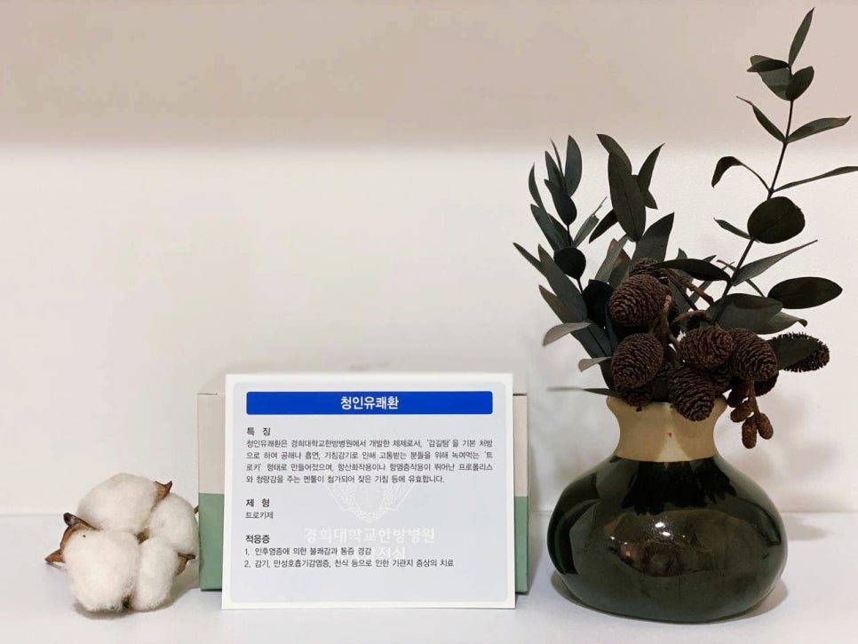 경희대학교한방병원 청인유쾌환 제품 상자가 목화솜과 마른 식물 장식 옆에 놓여 있다 — 서울 바로한의원 초음파 약침·도침