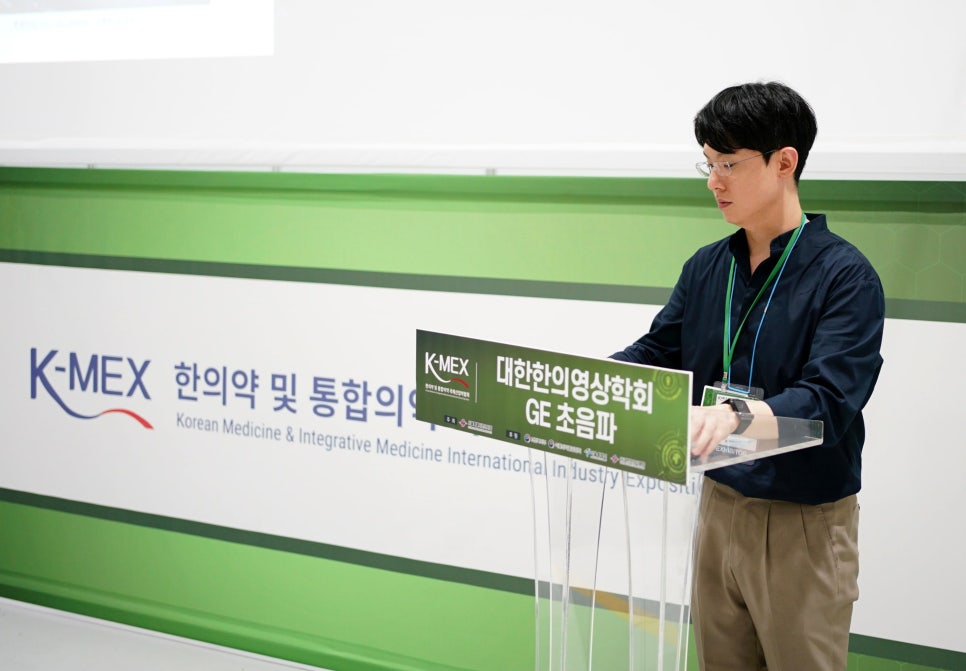 K-MEX 한의약 및 통합의학 박람회에서 한 남성이 연단에서 대한한의영상의학회 GE 초음파 관련 발표를 하고 있다 — 대한한의영상학회 초음파 약침·도침 강의 | 서울 바로한의원 안태석 원장