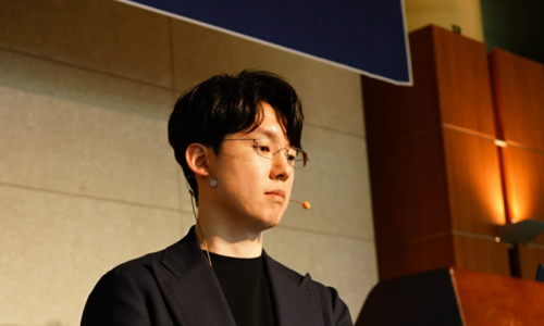안경을 쓴 남성이 마이크를 착용하고 강단에서 아래를 보고 있다 — 대한한의영상학회 초음파 약침·도침 강의 | 서울 바로한의원 안태석 원장