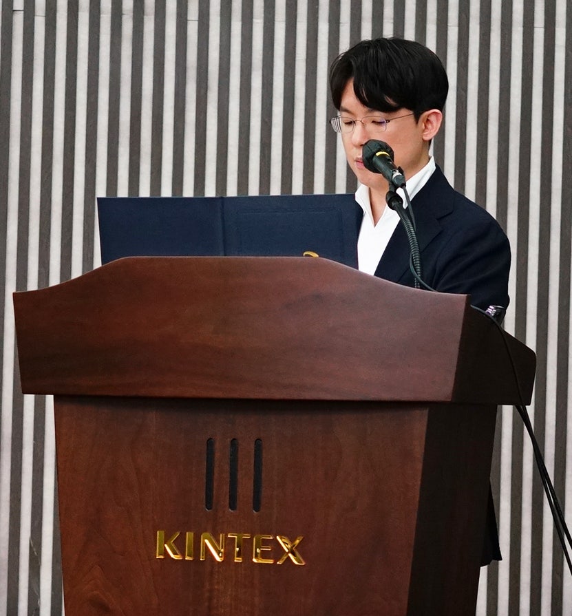 KINTEX 로고가 있는 연단에서 안경을 쓴 남성이 마이크 앞에서 발표하고 있다 — 대한한의영상학회 초음파 약침·도침 강의 | 서울 바로한의원 안태석 원장