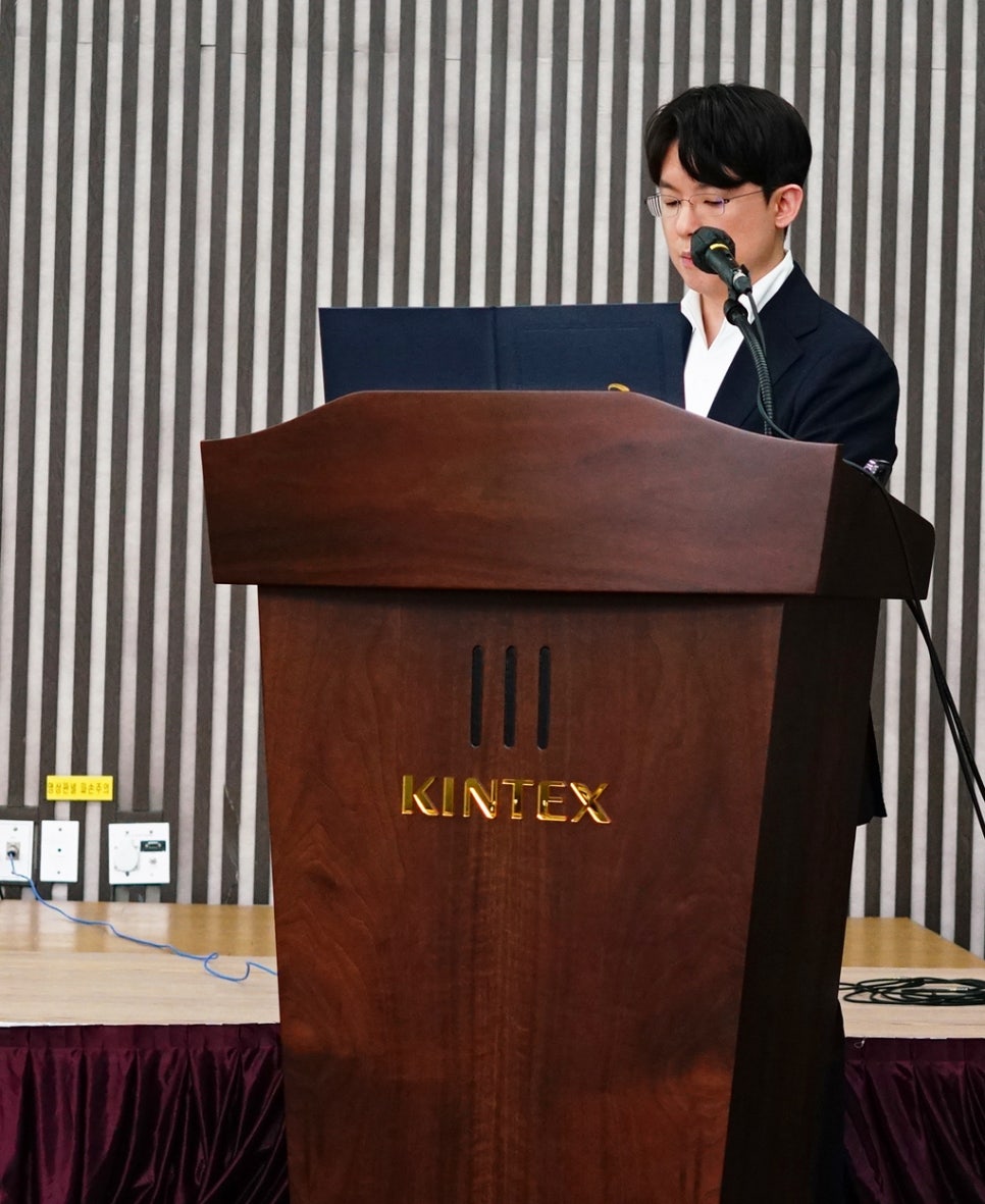 한 남성이 킨텍스 로고가 있는 연단에서 마이크를 잡고 발표하고 있다 — 대한한의영상학회 초음파 약침·도침 강의 | 서울 바로한의원 안태석 원장