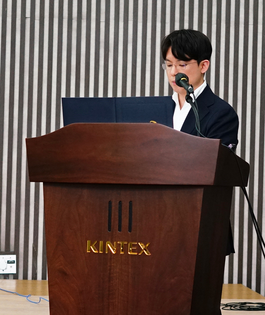 안경을 쓴 남성이 마이크 앞에서 나무 연단에 서서 발표하고 있다. 연단에는 KINTEX라고 쓰여 있다 — 대한한의영상학회 초음파 약침·도침 강의 | 서울 바로한의원 안태석 원장