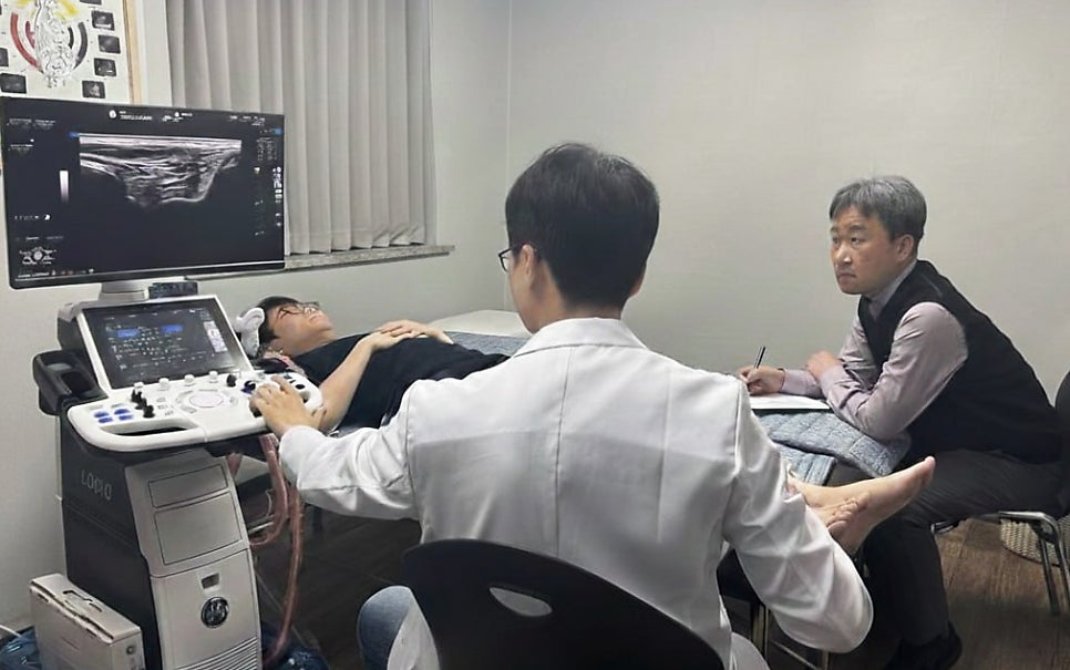 한의사가 환자의 다리에 초음파 검사를 하고 있으며, 초음파 화면이 보이고 다른 한의사가 이를 지켜보고 있다 — 초음파 정밀 진단 | 서울 바로한의원 초음파 약침·도침·침도