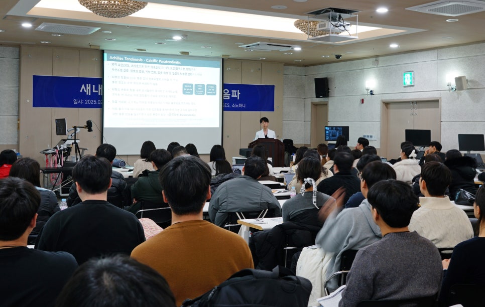 스크린에 아킬레스건염 관련 내용이 표시된 강의실에서 강사가 청중에게 발표하고 있다 — 대한한의영상학회 초음파 약침·도침 강의 | 서울 바로한의원