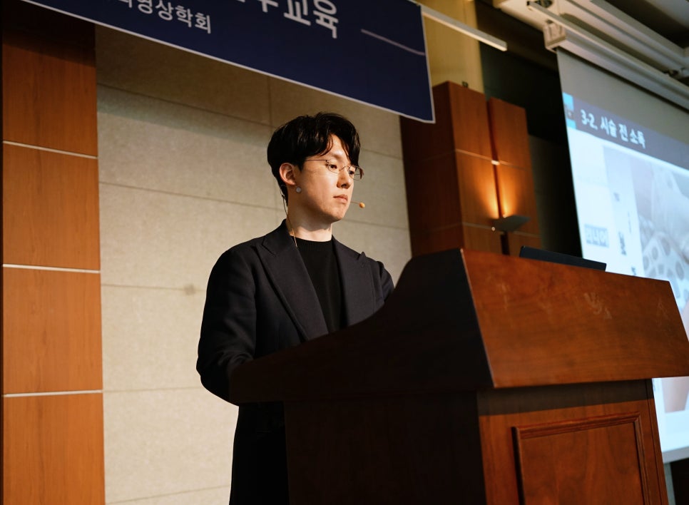 마이크를 착용한 남성이 강단에서 강연하고 있다 — 대한한의영상학회 초음파 약침·도침 강의 | 서울 바로한의원 안태석 원장