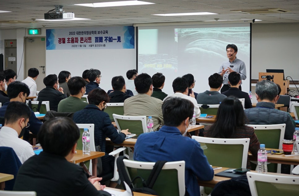 강사가 강당에서 청중에게 초음파 보수교육을 진행하고 있다 — 대한한의영상학회 초음파 약침·도침 강의 | 서울 바로한의원