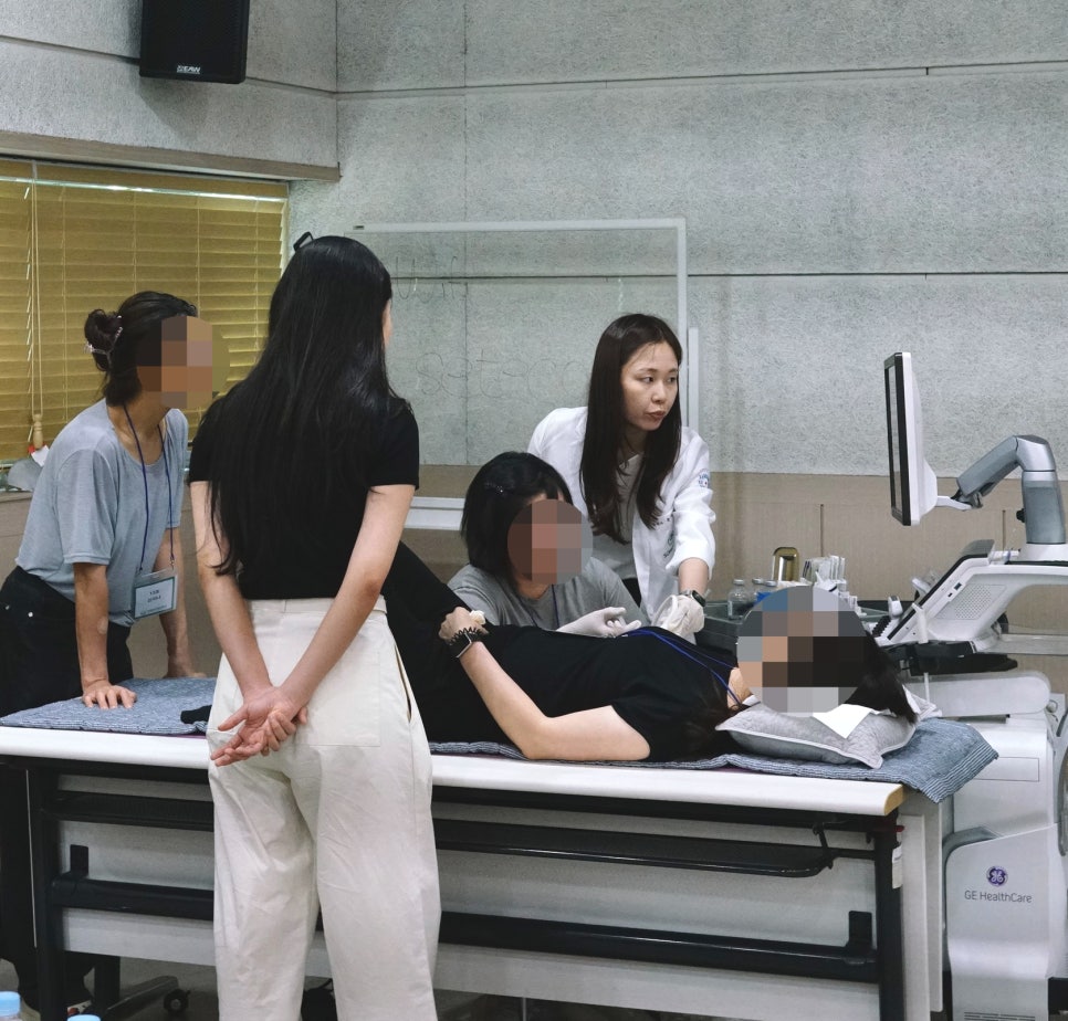 여러 사람이 초음파 기기와 환자를 중심으로 모여 약침 시술을 실습하는 모습 — 대한한의영상학회 초음파 약침·도침 강의 | 서울 바로한의원