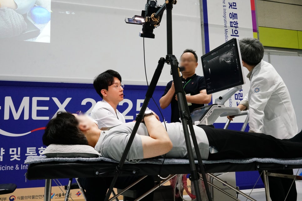환자가 침대에 누워 있고, 한의사가 옆에 앉아 있으며, 다른 한의사가 초음파 기기를 조작하여 모니터에 초음파 영상이 보이는 장면 — 초음파 정밀 진단 | 서울 바로한의원 초음파 약침·도침·침도
