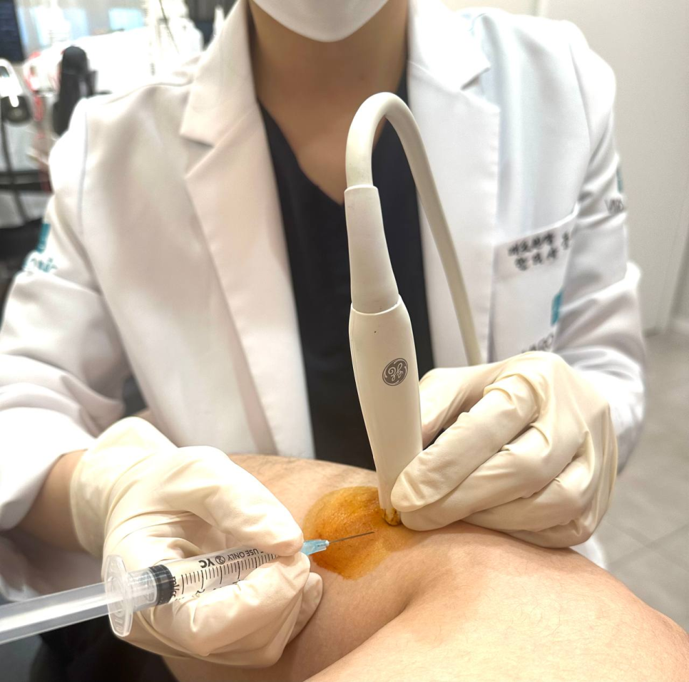 의료진이 환자의 다리에 초음파 유도 주사를 시술하고 있다. 주사 부위는 소독되어 있다 — 초음파 유도하 약침 시술 | 서울 바로한의원