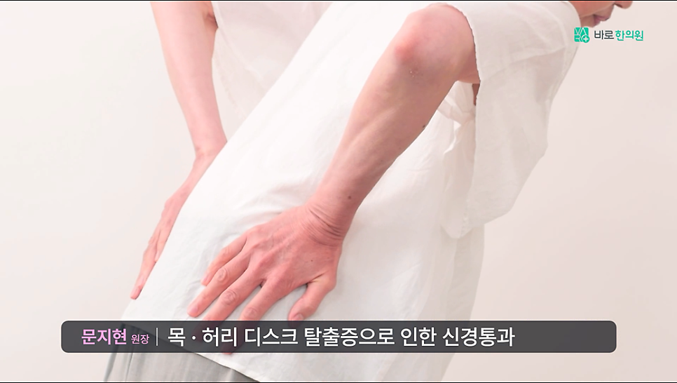 흰 상의를 입은 사람이 허리를 숙인 채 양손으로 허리를 짚고 있는 뒷모습 — 서울 바로한의원 초음파 약침·도침